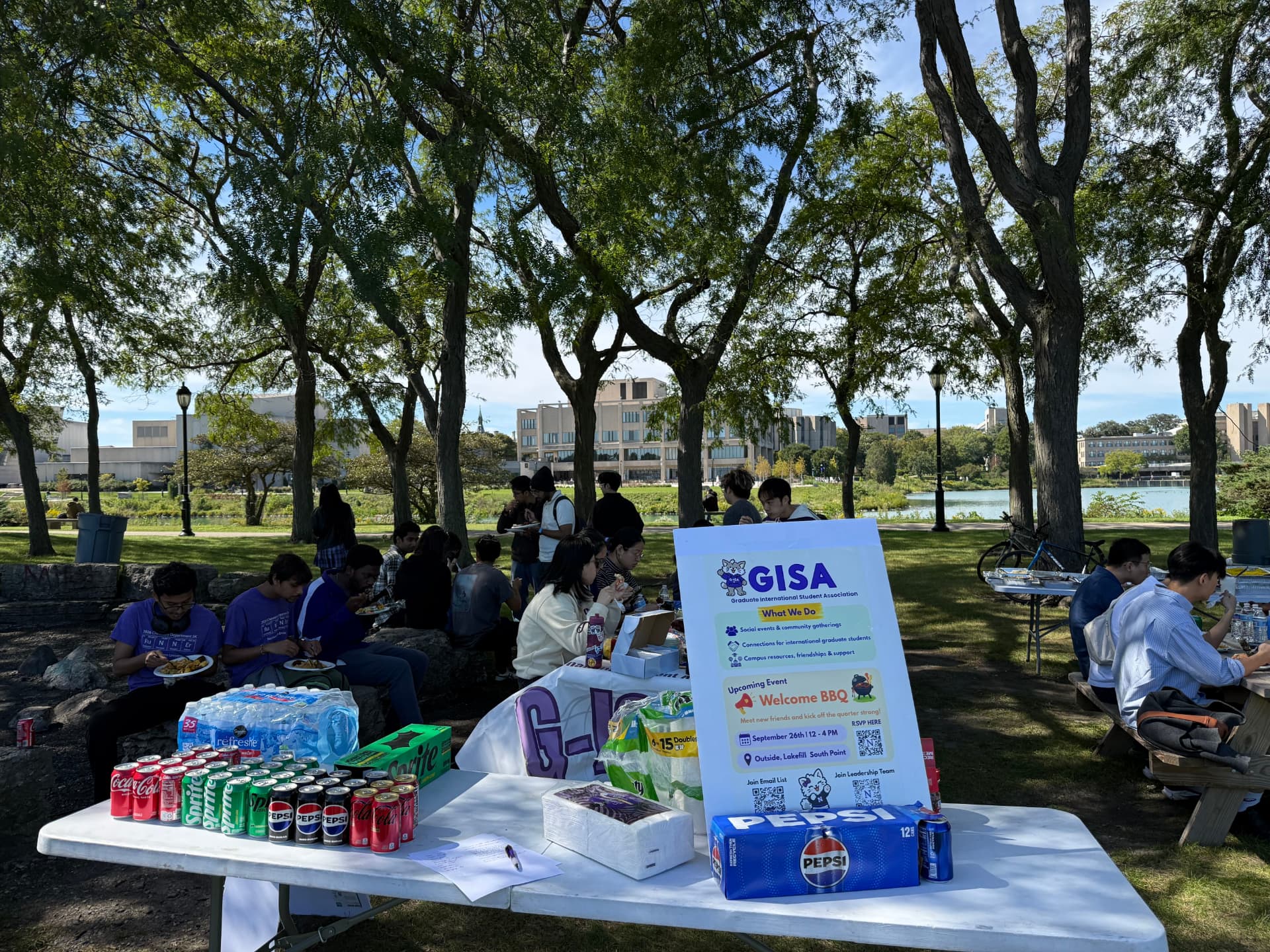 G-ISA welcome table with drinks and snacks on the Lakefill South Point lawn as students gather for the BBQ