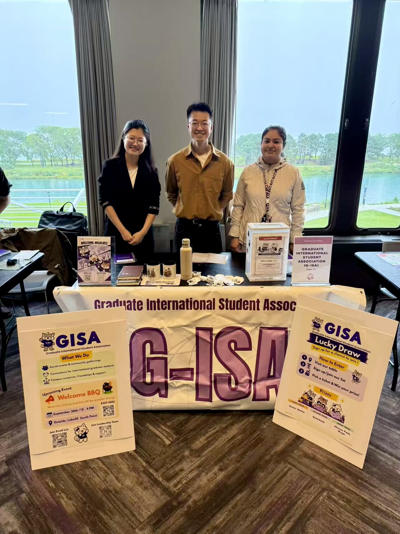 G-ISA leadership at the resource fair table with the G-ISA banner, Welcome Wildcats materials, and Lucky Draw box